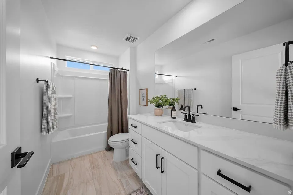 Spacious vanity with under-mount sink, expansive mirror, white cabinetry, and matte black hardware