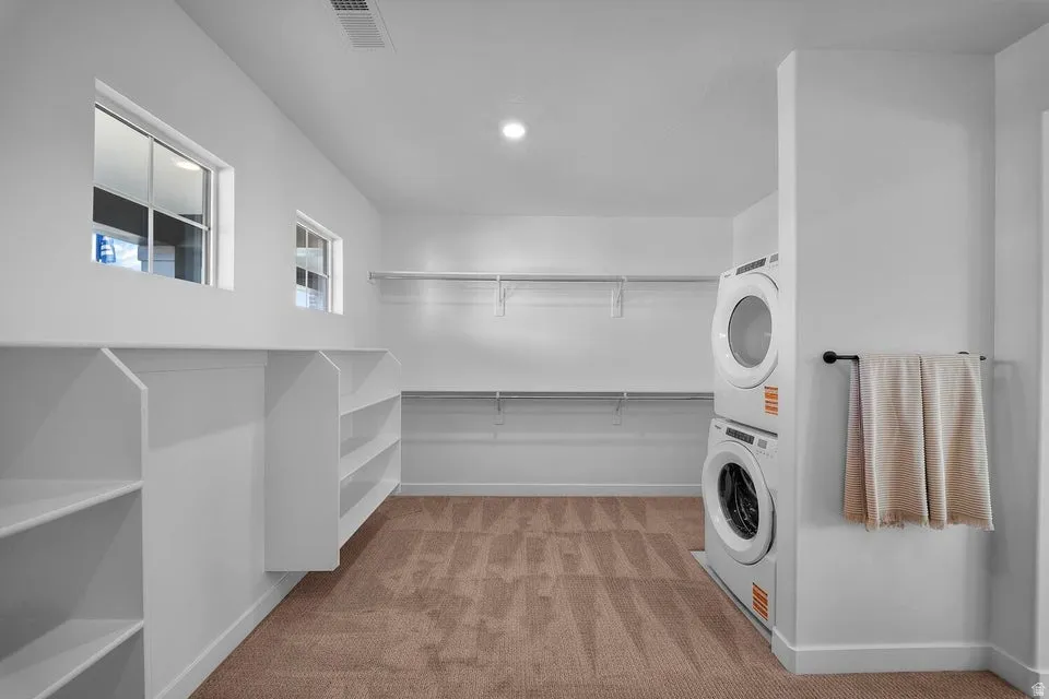 Built-in shelving and hanging rods providing storage solutions, dual windows, and stacked laundry appliances