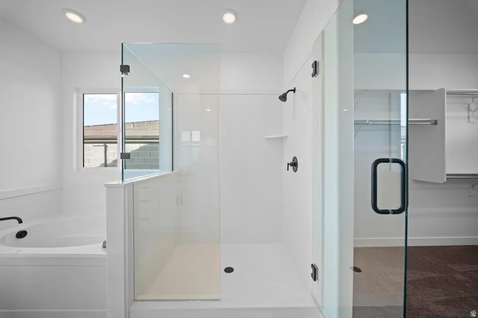 Glass-enclosed shower with matte black fixtures, built-in shelf, and recessed lighting