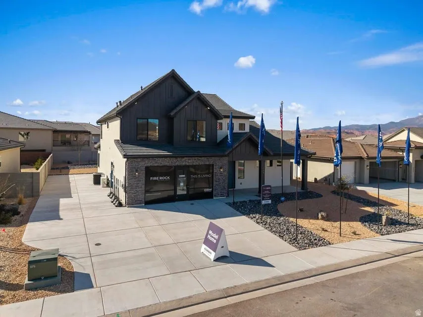 Contemporary two-story exterior with stone and siding accents, expansive concrete driveway, and low-maintenance xeriscape landscaping