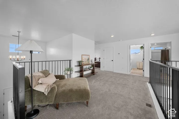 Spacious carpeted landing featuring black metal railings, recessed lighting, and white interior doors