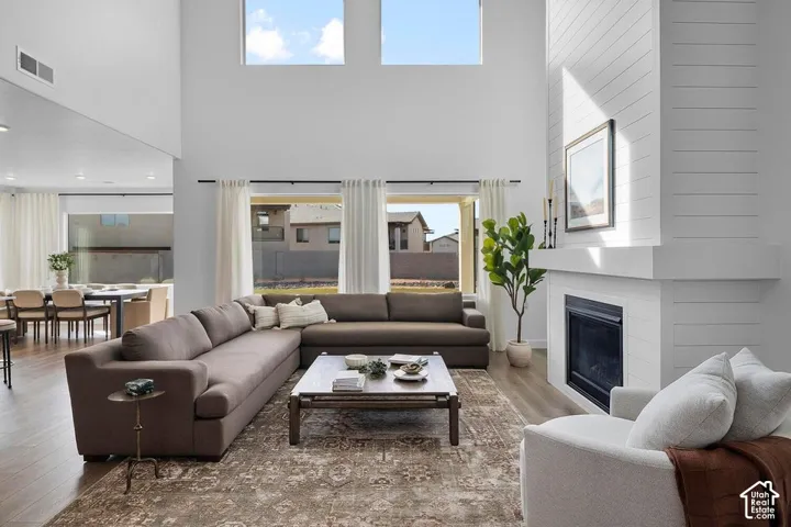 Two-story living area with wood-finish flooring, a contemporary fireplace with shiplap accent, and large windows