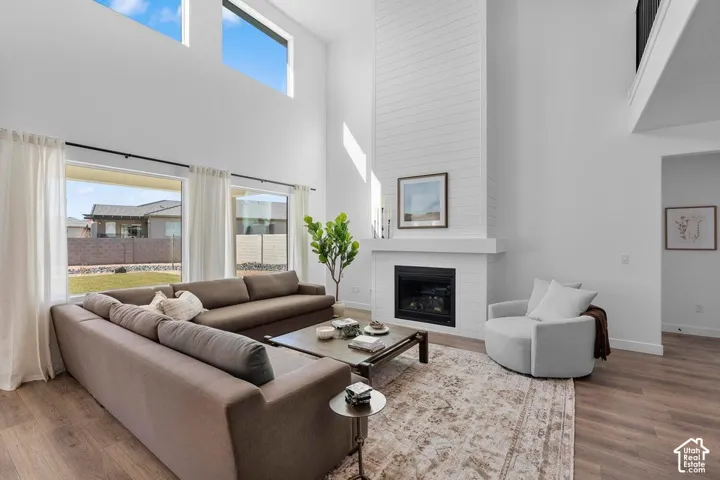Wood-finish flooring throughout, paired with a floor-to-ceiling fireplace featuring a white shiplap-style finish