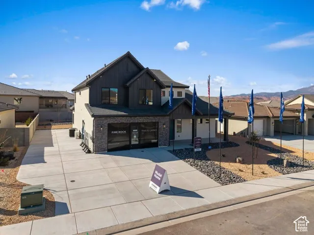 Contemporary two-story exterior with stone and siding accents, expansive concrete driveway, and low-maintenance xeriscape landscaping