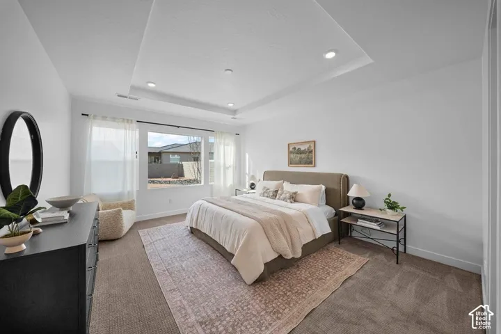Spacious room with large windows, recessed lighting, a tray ceiling, and neutral carpeting