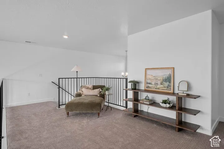 Carpeted loft area featuring a dark metal railing, recessed lighting, and a contemporary wall console