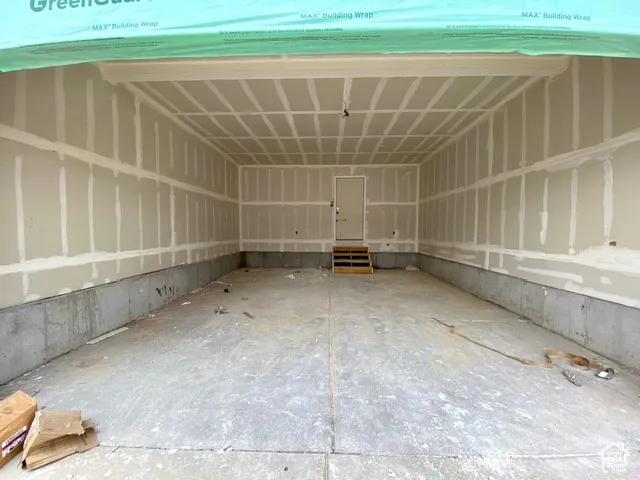Spacious garage featuring a concrete floor, framed walls, and an interior access door with steps