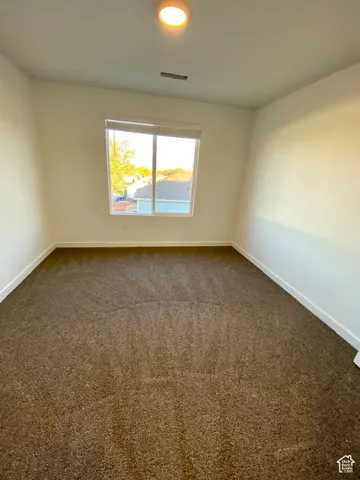 Neutral wall color, wall-to-wall carpeting, window with roller shade, and overhead lighting fixture