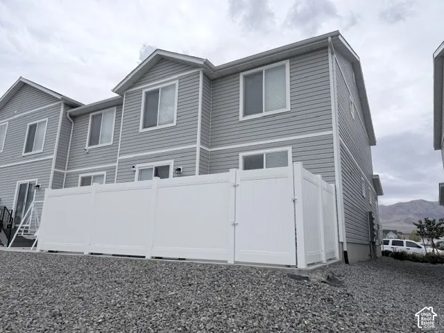 Multi-level exterior featuring horizontal siding, white trim accents, and a private white vinyl privacy fence enclosing the rear exterior space