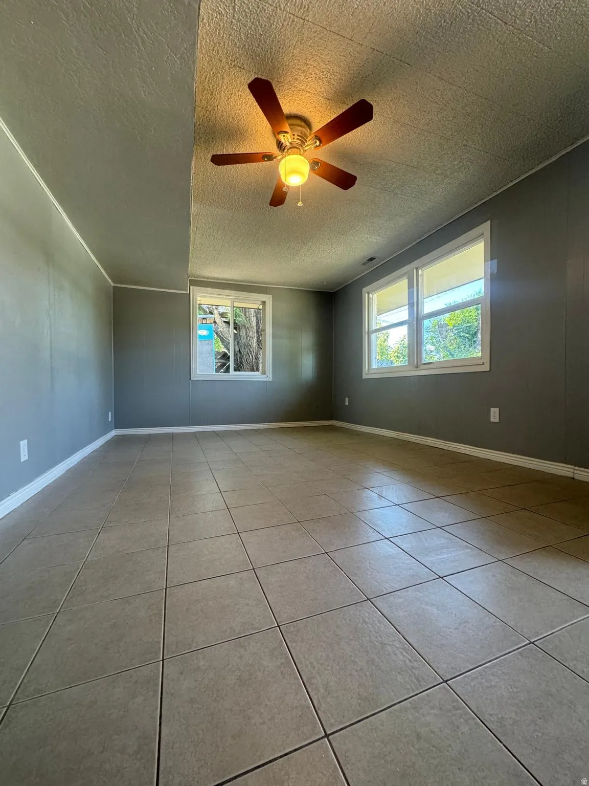 Tile flooring throughout with multiple windows and a ceiling fan