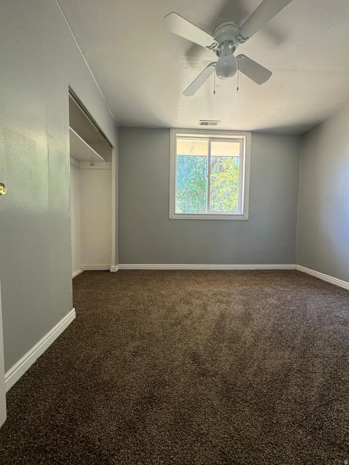 Plush carpet flooring, neutral wall tones, white trim, a multi-pane window, and a ceiling fan with integrated lighting
