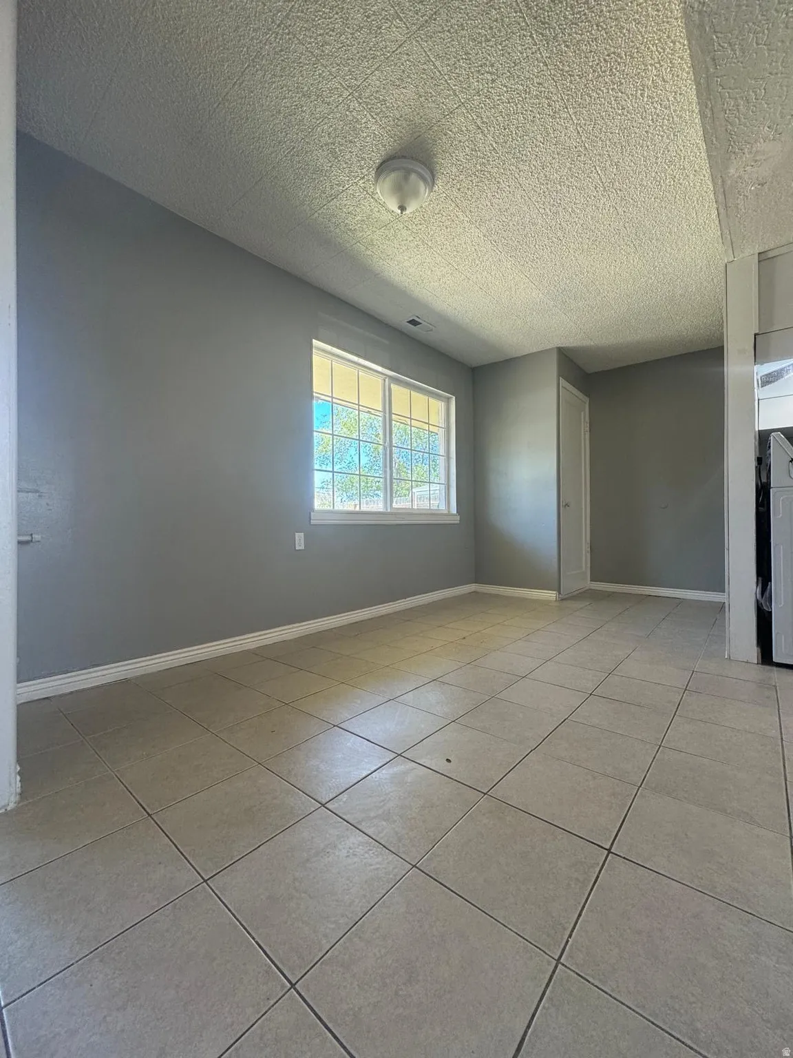 Tile flooring, window with grilles, flush mount ceiling light fixture, neutral wall paint, white trim