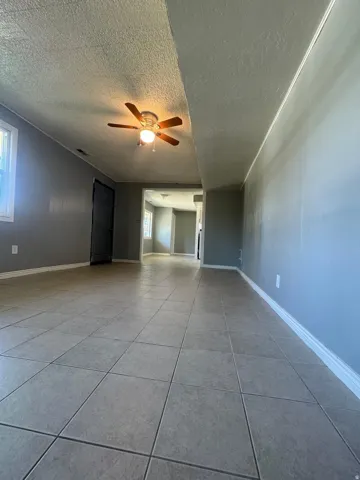 Spacious room featuring tile flooring, painted walls, and a ceiling fan with integrated lighting