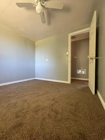 Neutral wall paint, brown carpet flooring, and a white ceiling fan with integrated lighting
