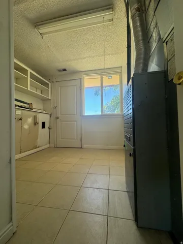 Recessed cabinetry, tile flooring, window, and a utility door