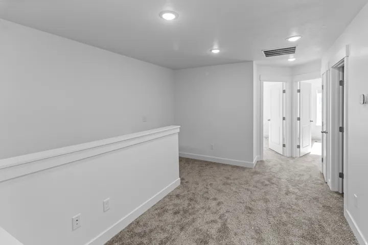 Carpeted open landing with recessed lighting, white trim, and multiple doorways