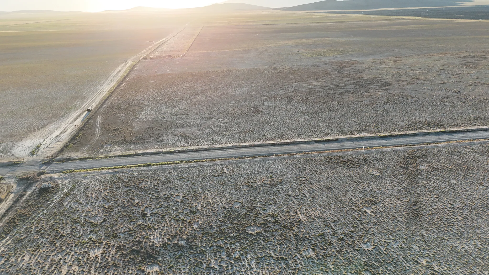 Expansive lot with a dirt road, an unpaved pathway, and distant mountains