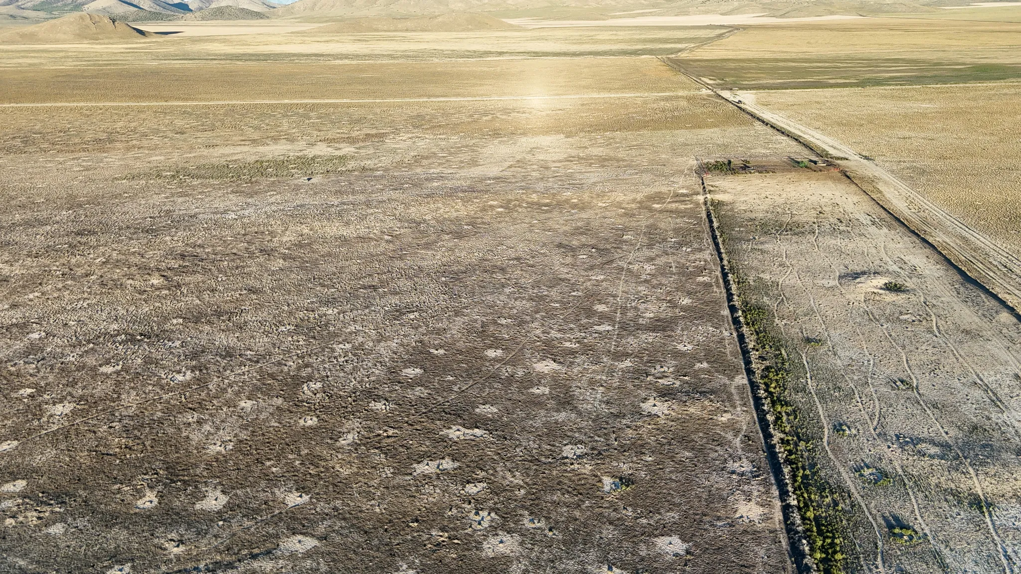 Expansive undeveloped land with natural vegetation, featuring a defined property boundary and distant mountain ranges