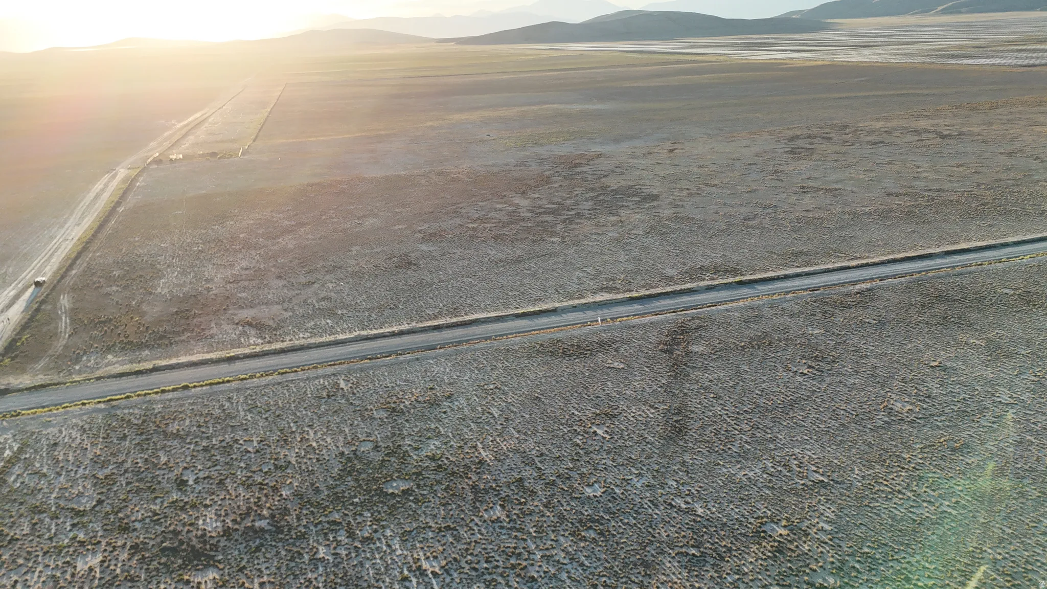 Expansive open land with two distinct unpaved roads and distant mountain backdrop