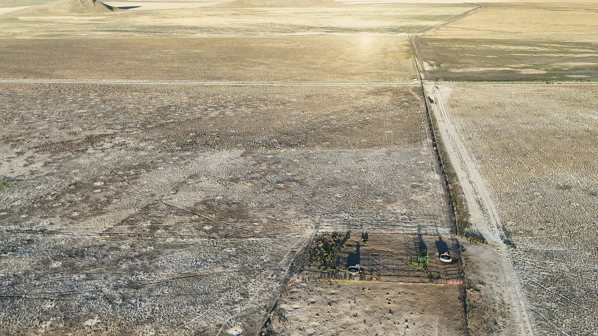 Expansive open land featuring diverse terrain, distinct property lines, and a visible access road