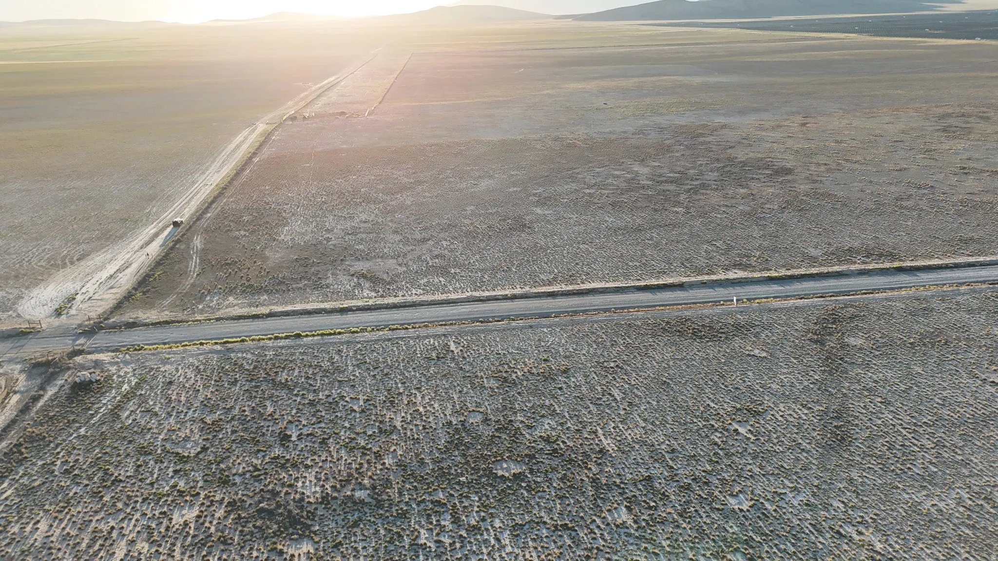 Expansive flatland with intersecting unpaved roads and distant elevated terrain