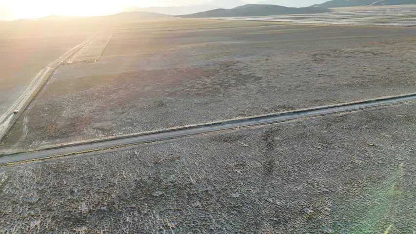 Expansive open land with two distinct unpaved roads and distant mountain backdrop