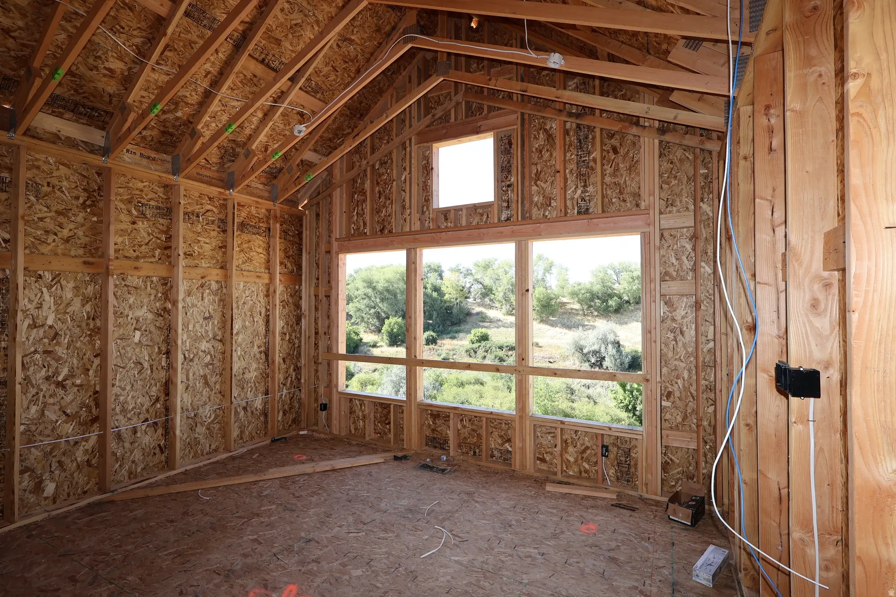 Vaulted wood-framed ceiling with exposed joists, large multi-pane windows, and an additional upper window, all set within a wood-framed structure