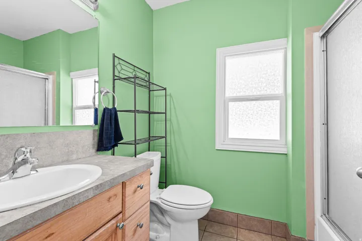 Single vanity with an oval sink, chrome faucet, and integrated backsplash
