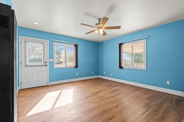 Wood-finish flooring, two windows, and a ceiling fan with integrated lighting