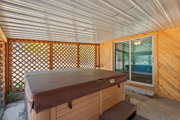Covered patio with corrugated metal roof, wood-finish walls, and lattice privacy panels