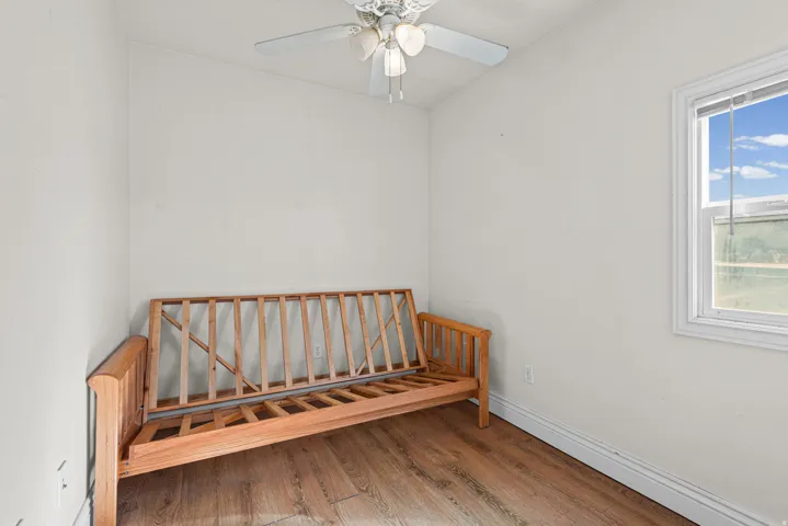Wood-finish flooring, white walls, white trim, single window, and a ceiling fan with integrated lighting