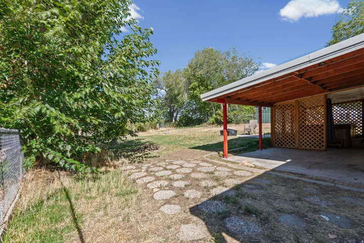 Covered outdoor patio with lattice screening, concrete flooring, and a stepping stone pathway