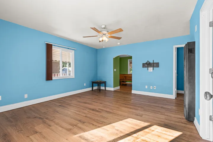 Spacious open room showcasing wood-finish flooring, bright blue walls, and abundant natural light from multiple windows