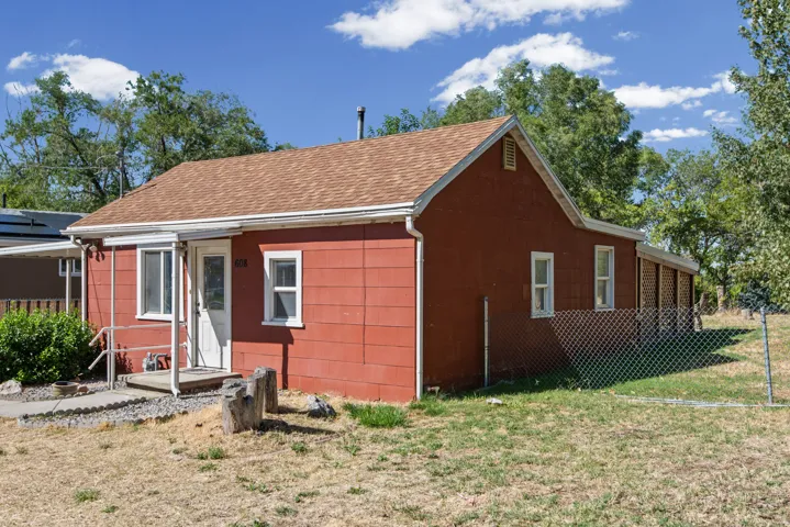 Red exterior siding with white trim, brown shingle roof, and a covered front porch featuring white railings