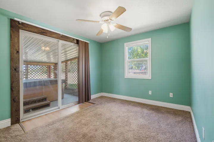 Room featuring a ceiling fan, window, and sliding glass door with wood-finish trim