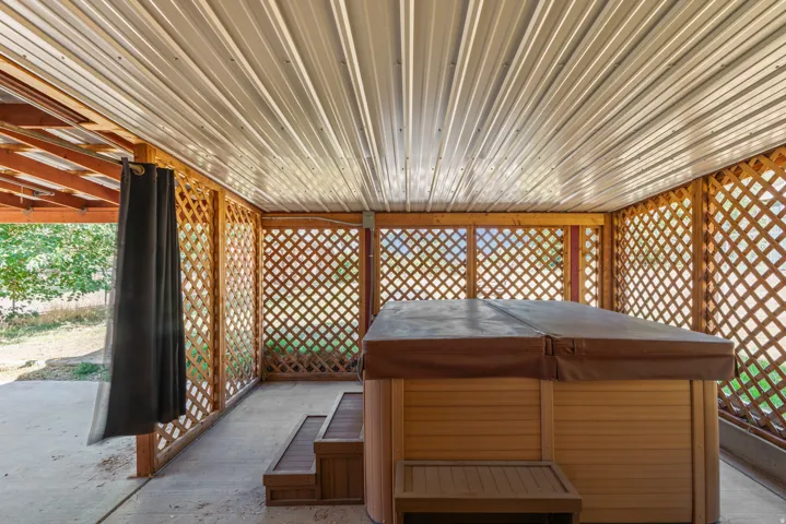 Covered patio with a corrugated metal ceiling, wood lattice screens, and a built-in spa