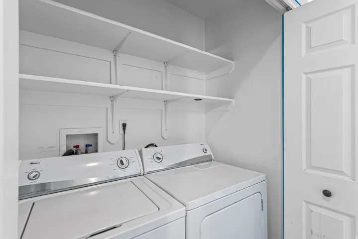 Dedicated laundry area featuring a washer and dryer, integrated shelving, and white paneled door