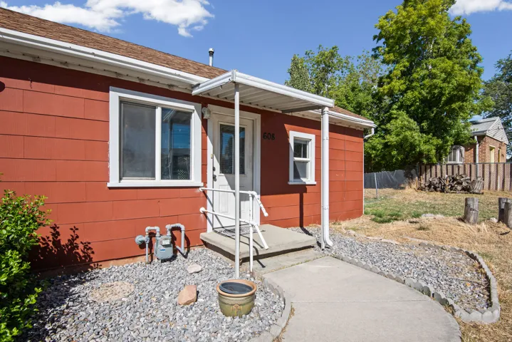 Red-sided exterior with white trim, a covered front entry, and a concrete pathway