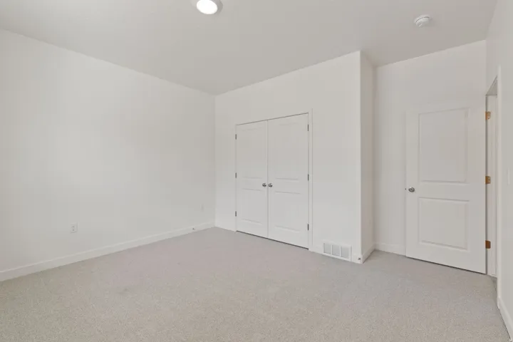 Carpeted flooring, white walls, recessed ceiling light, white paneled doors, and a built-in closet