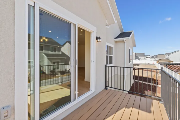Balcony with composite decking, black metal railing, and exterior wall sconce