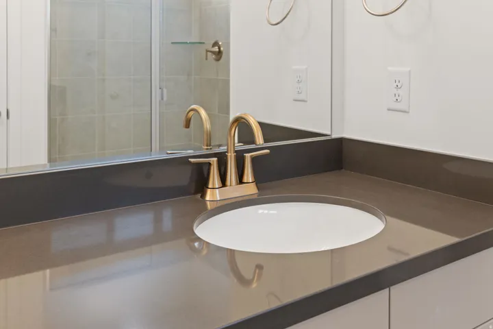 Integrated vanity with a bronze-toned faucet, undermount sink, and expansive mirror