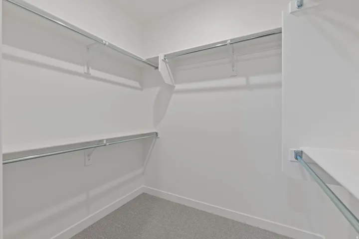 Built-in closet system with multiple shelves and hanging rods, complemented by gray carpeting