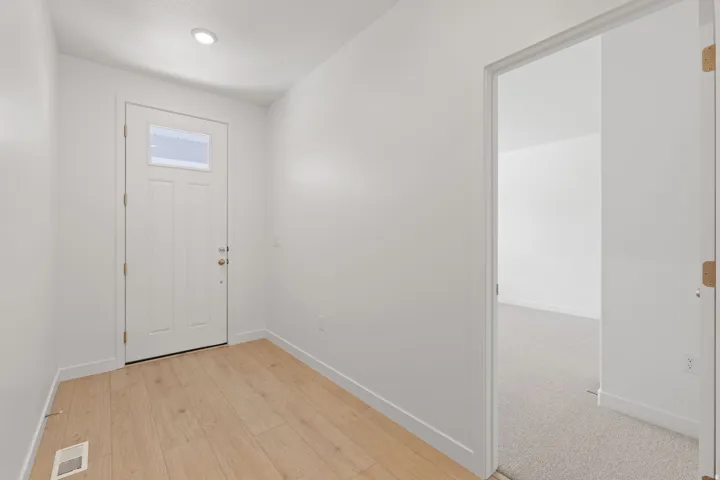 Entryway featuring wood-finish flooring, recessed lighting, and a white paneled door with an upper glass insert