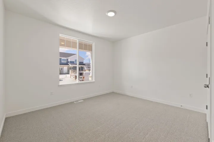 Neutral-toned carpeting, white walls, and a window with white trim