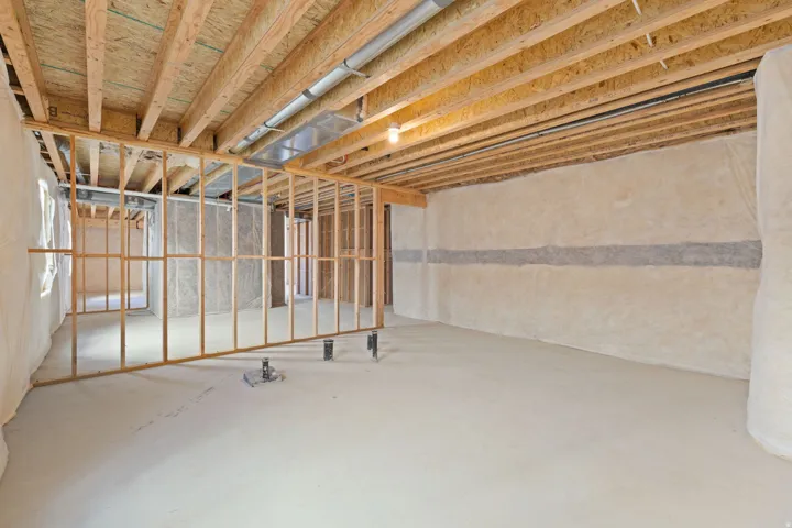 Unfinished basement with exposed wood framing, concrete flooring, and visible insulation