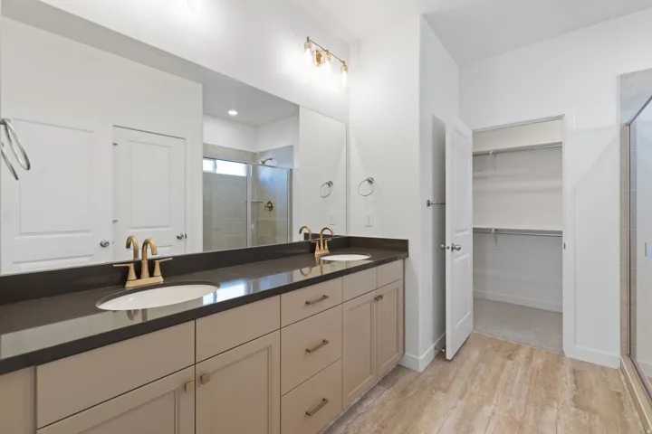 Dual vanity with undermount sinks, bronze finish fixtures, and a dark stone-look countertop