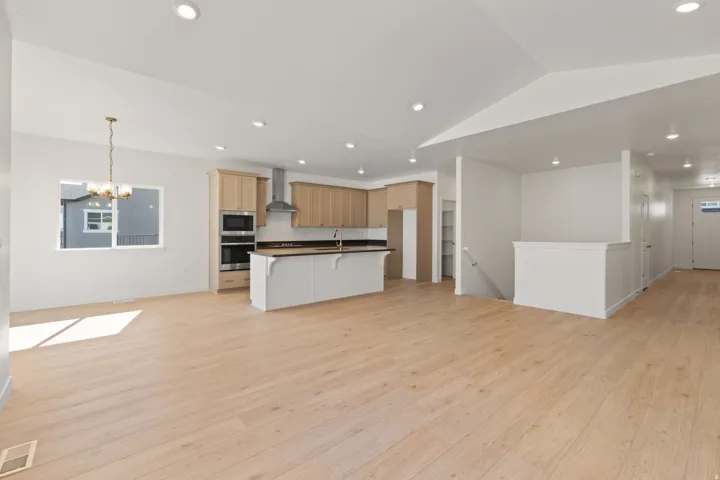 Open-concept living area with wood-finish flooring, recessed lighting, and a modern kitchen
