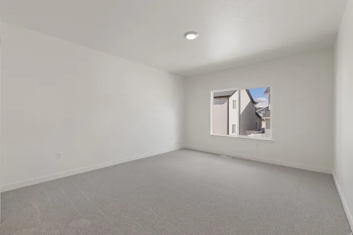 Neutral paint palette, recessed ceiling light, white window trim, and light gray carpeting