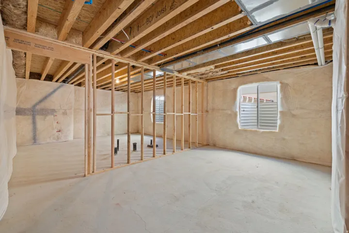 Unfinished basement with concrete flooring, framed interior walls, and exposed ceiling joists
