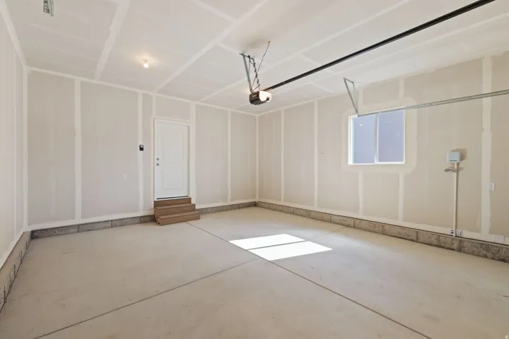Concrete flooring, interior access door with wood steps, built-in window, and exposed garage door mechanisms